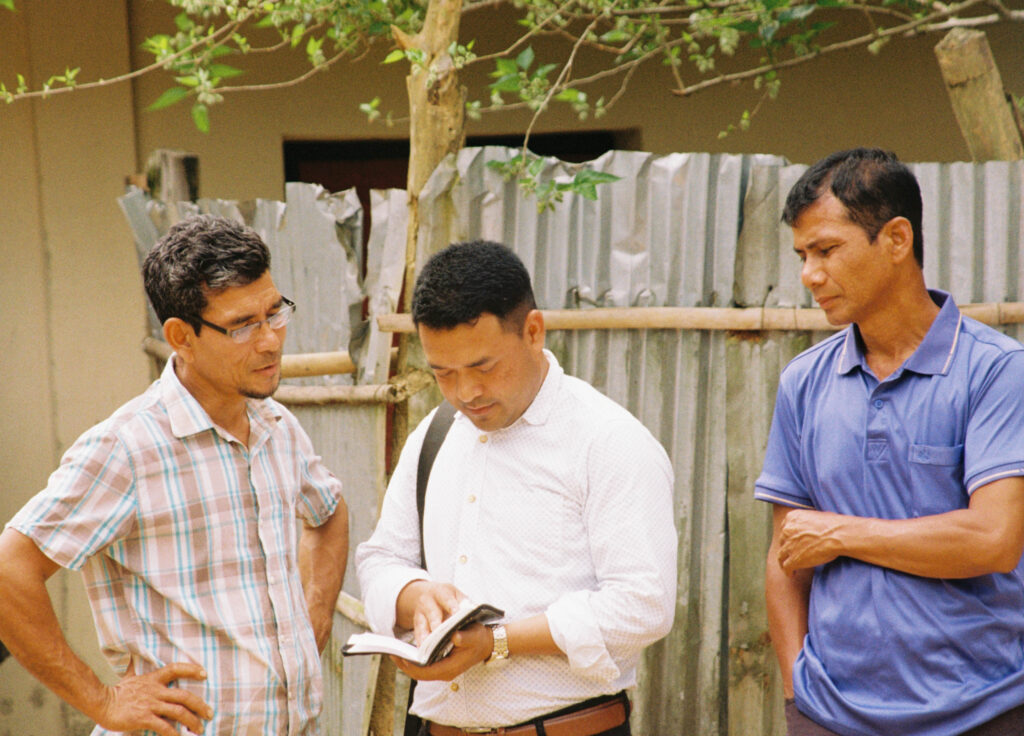 Tre menn diskuterer bibelen, i en landsby